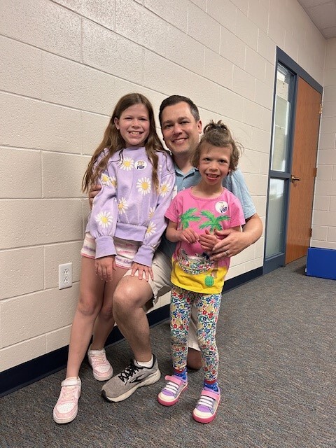 2 young female students pose with their dad