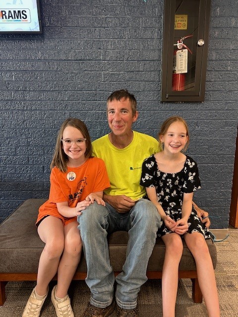 2 young female students pose with Dad