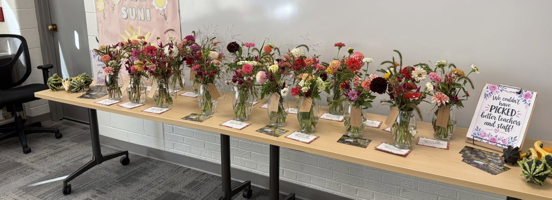 Vases of flowers on a long table with notes from students. 