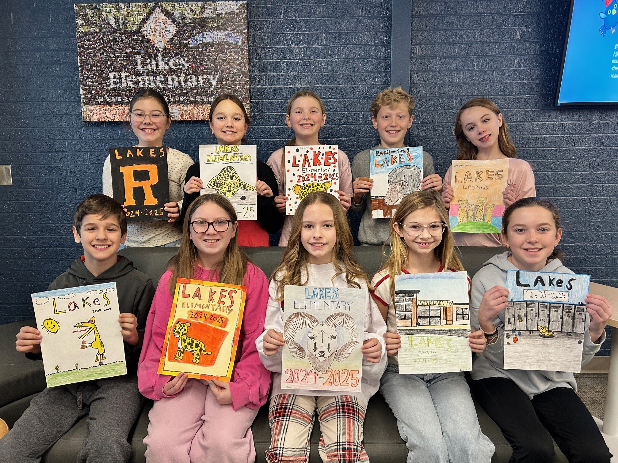 10 students smiling and holding their yearbook cover entries